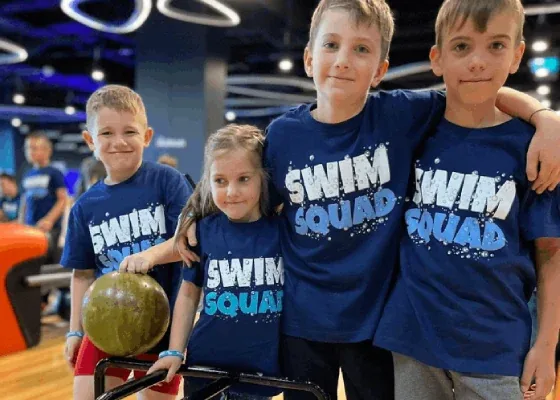 Dzieci w koszulkach Swim Squad z kulą do kręgli podczas półkolonii w Łodzi